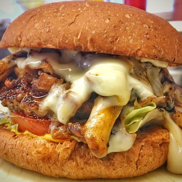 Close-up of a Bubba's Texas Burger Shack burger with melted cheese, grilled onions, lettuce, and tomato.