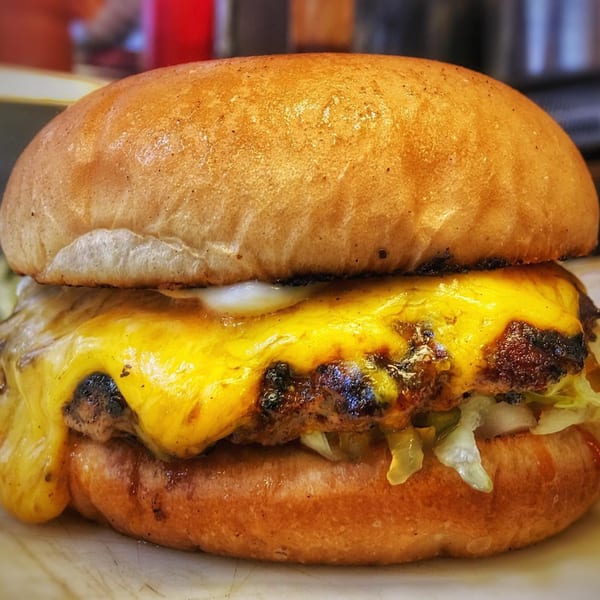 Close-up of a Bubba's Texas Burger Shack burger with melted cheese, lettuce, and sauce.