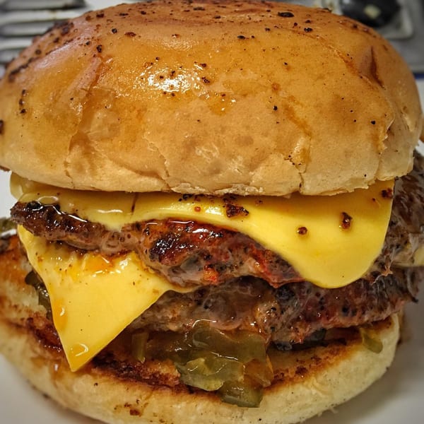 Close-up of a Bubba's Texas Burger Shack double cheeseburger with melted cheese and jalapeños.