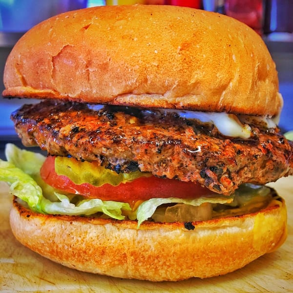 A Bubba's Texas Burger Shack burger with a grilled patty, melted cheese, lettuce, tomato, and pickles.